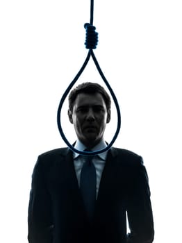 one caucasian business man standing in front of hangmans noose in silhouette studio isolated on white background