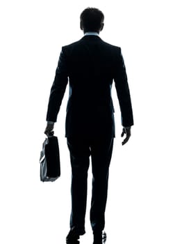 one caucasian businessman walking rear view in silhouette studio isolated on white background