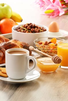Breakfast including coffee, bread, honey, orange juice, muesli and fruits