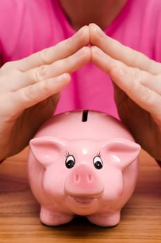 Two female hands over a pink piggy bank