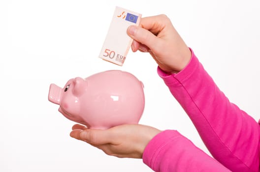 Female hand puts euro bill in a pink piggy bank