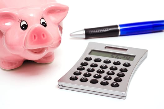 Pink piggy bank and a ballpoint pen with calculator