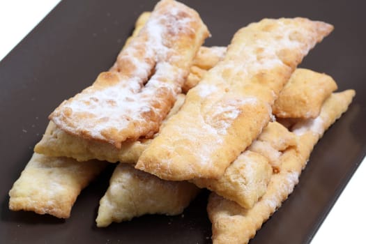 Details of "Angel wings"" or ""bugnes"" are a french traditional sweet crispy pastry made out of dough that has been deep-fried and sprinkled with powdered sugar."