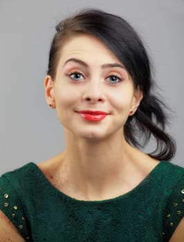 Portrait of a beautiful young woman with green dress over grey.
