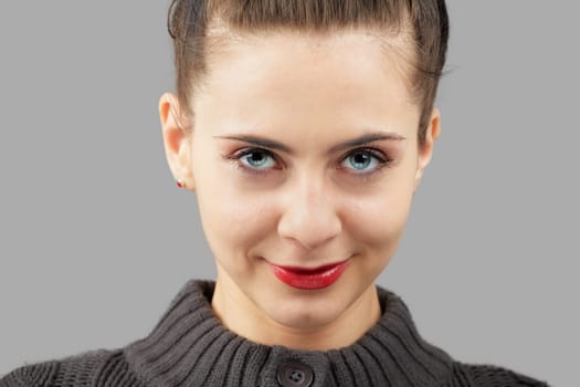 Portrait of a beautiful young woman with blue eyes isolated on grey