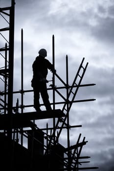 silhouette of construction worker on scaffolding, Blue toned