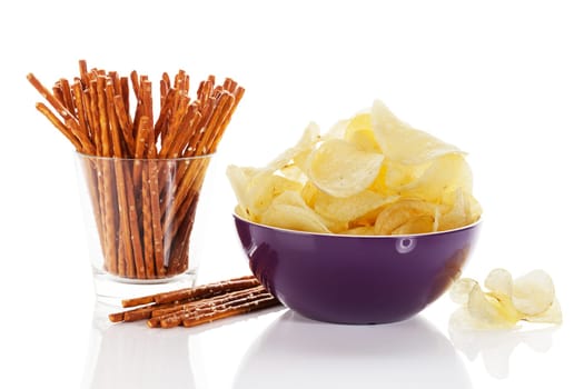 Chips and pretzel sticks on white background