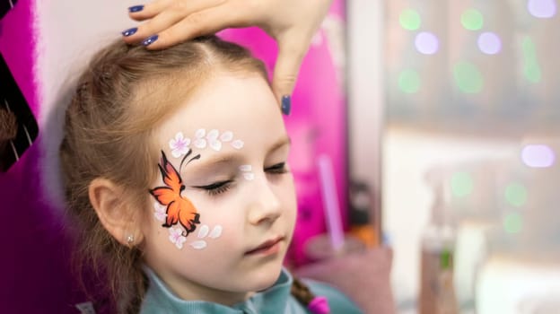 childrens makeup face paint drawings Girls face painting. Little girl having face painted on birthday party. closed eyes. High quality photo