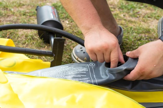 a man inflates a rubber boat with a pump. pump close-up. The text of the safety instructions is written in English. High quality photo