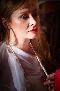 Beautiful European girl looking like Arab woman in red room with rich fabrics and carpets in sultan harem. Photo shoot of an oriental style odalisque. A model poses in sari as indian woman in india