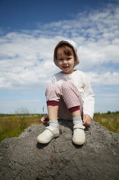 Portrait of little girl with Asian eyes in a meadow or field with grass and flowers on a sunny summer day