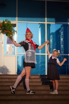 Young and adult schoolgirl on September 1 with flowers. Generations of schoolchildren of USSR and Russia. Female pioneer in red tie and October girl in modern uniform. Daughter and Mother having fun