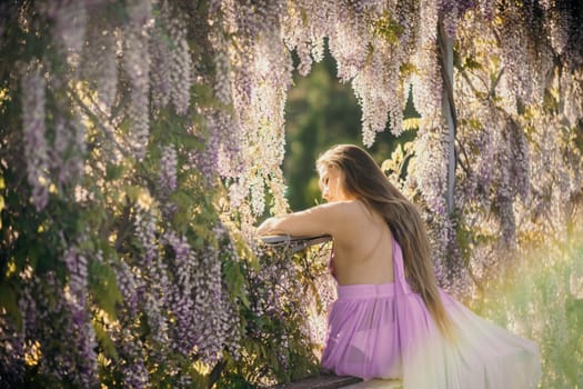 Woman wisteria lilac dress. Thoughtful happy mature woman in purple dress surrounded by chinese wisteria.