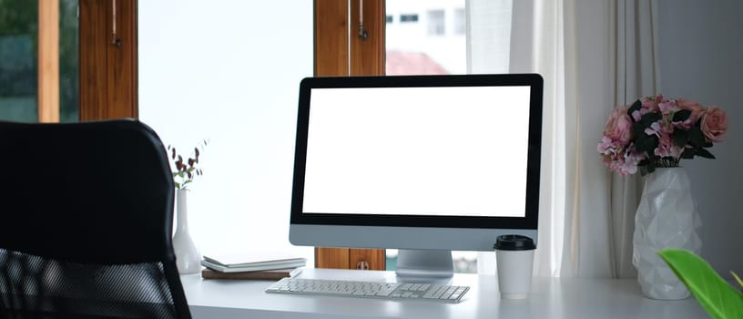 Blank computer monitor, pink roses in vase and books on white table. Empty screen for your advertising text message.