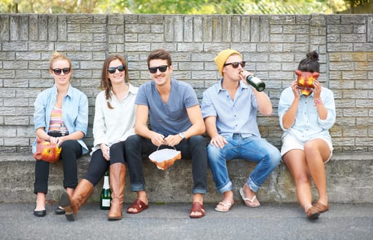 Drinks, portrait and friends on a bench in public for costume masks, conversation and bonding on the weekend. Happy, group and people in the city for alcohol, communication and together for society.