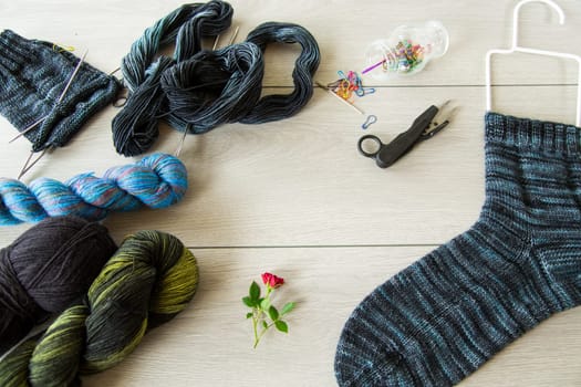 Set for hand knitting warm winter socks made of natural woolen yarn, on a wooden table.