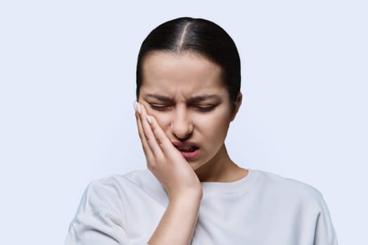 Teenage girl having toothache, on white studio background. Dental health, teenagers, young people concept