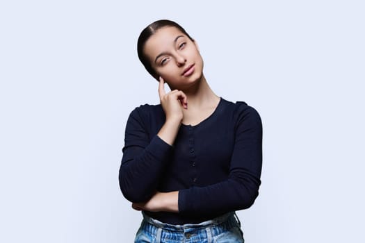 Portrait of teenager girl looking at camera on white studio background. Smiling teenage female 15, 16 years old. Adolescence, high school student, youth concept