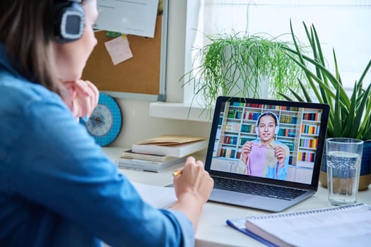 Young female teacher in headphones having video conference call with teenage girl student using laptop home. Online lesson e-learning distance remote classes technology in education knowledge school