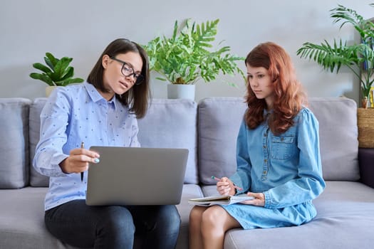 Individual lesson of teacher and child of preteen girl. Young woman teaching child, using laptop, student makes notes in notebook. Knowledge, education, teaching, tuition, school childhood concept