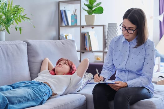 Psychologist helping teenage female, individual therapy in doctors office. Professional counselor listening teenager, girl lying on couch. Mental health, adolescence, psychology, psychiatry concept