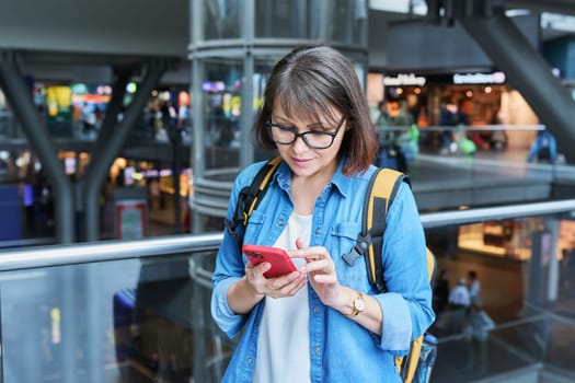 Woman on in modern building of city transport station with smartphone. Female using fast internet connection network for online ticketing service mobile application timetable transport route