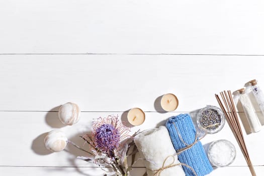 Spa products. Bath salts, dry flowers lavender, soap, candles and towel. Aroma sticks, aromatherapy. Flat lay on white wooden background, top view. Still life. Close-up. Copy space