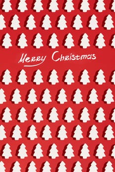 Pattern made of white christmas decoration with christmas tree on red background. Christmas wallpaper. Flat lay, top view