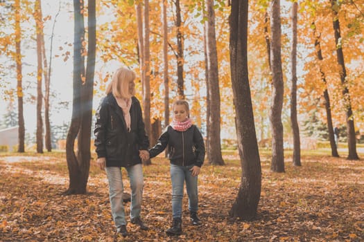 Grandmother with granddaughter in autumn park. Generations and family concept