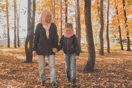 Grandmother with granddaughter in autumn park. Generations and family concept