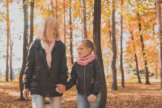 Grandmother with granddaughter in autumn park. Generations and family concept