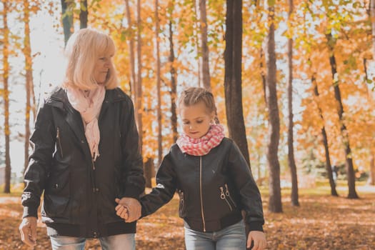 Grandmother with granddaughter in autumn park. Generations and family concept