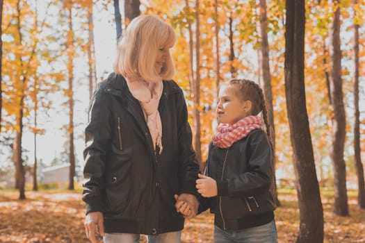 Grandmother with granddaughter in autumn park. Generations and family concept