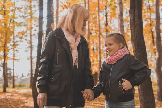 Grandmother with granddaughter in autumn park. Generations and family concept