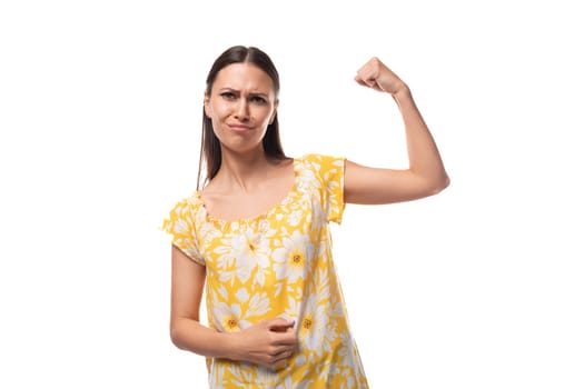 young woman with straight black hair in a yellow sundress with a print pattern shows her strength and confidence.