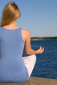 a young woman doing yoga in front of the sea