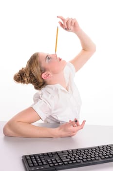 Young woman with blond hair wearing a business suit and get bored at a desk, they balance a pencil on her forehead, isolated against white background.
