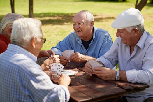 Active retirement, old people and seniors free time, group of four elderly men having fun and playing cards game at park. Waist up