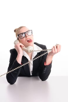 Young woman with blond hair wearing a business suit and has frustrated the computer. She sits at her keyboard and looks annoyed at the camera, isolated against white background.