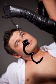 Couple playing sexual and domination games in a bedroom - handcuffs in focus.