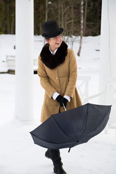 Young woman try close black umbrella on walk