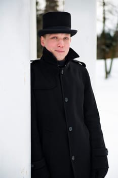 Young man in hat relies on white column
