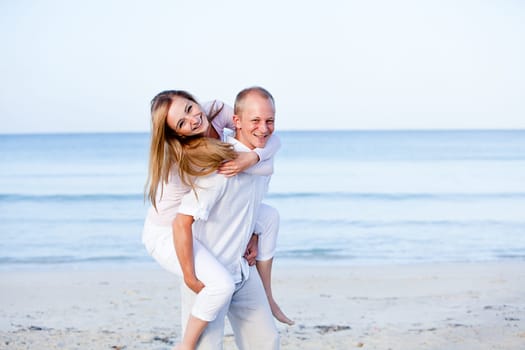Young happy couple in love having fun on the beach in summer