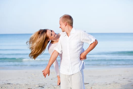 Young happy couple in love having fun on the beach in summer