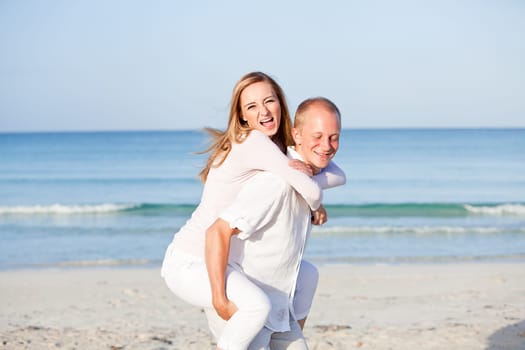 Young happy couple in love having fun on the beach in summer