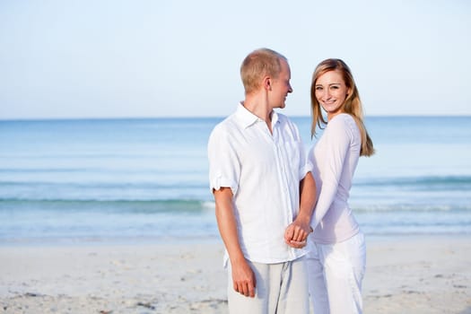 Young happy couple in love having fun on the beach in summer