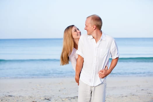 Young happy couple in love having fun on the beach in summer