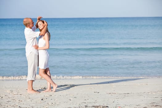 Young happy couple in love having fun on the beach in summer