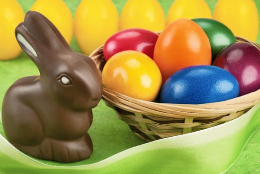 Chocolate Easter bunny and painted Easter eggs in a basket