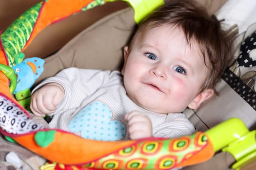 Portrait of a playing baby 7 months old, lying down on back